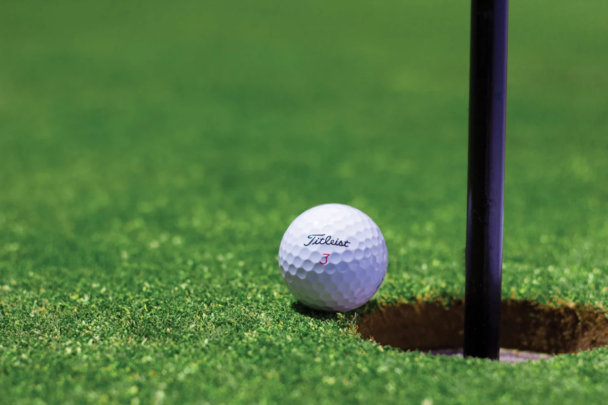 500504_981629 a golf ball sitting on the edge of a hole