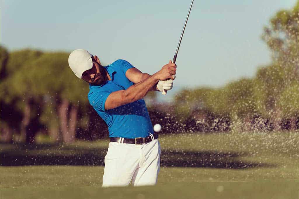 6 tips for playing golf in the wind 3 a man hitting a golf ball with his club