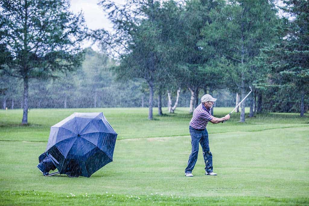6 tips for playing golf in the wind 1 6 Tips for Golfing in the Wind and a man playing golf in bad weather.