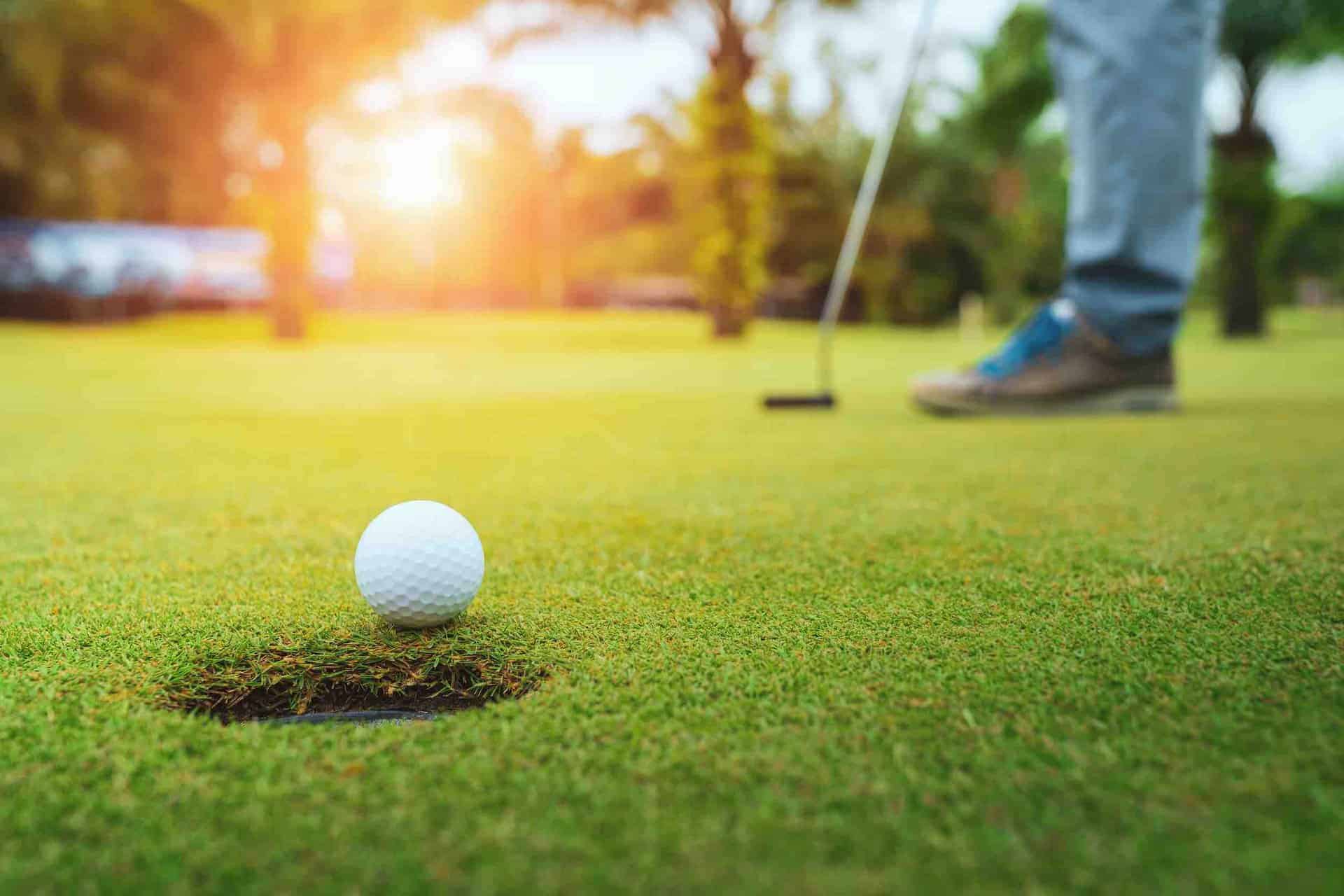 What is a Good Golf Score? 3 a golf ball sitting in the hole next to a man