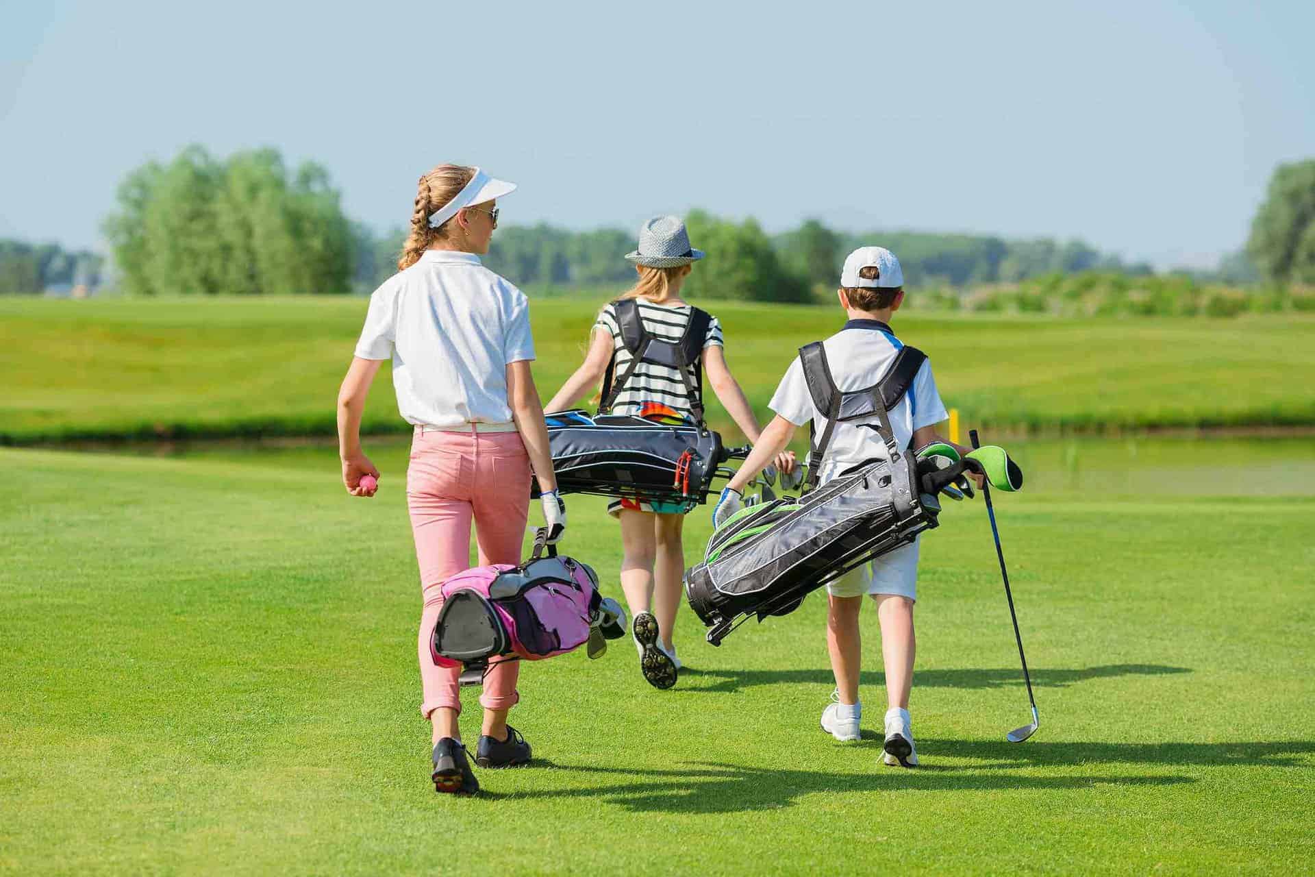Junior Golf Etiquette: 10 Rules to Teach Young Golfers 1 three junior golfers walking on a golf course with their clubs