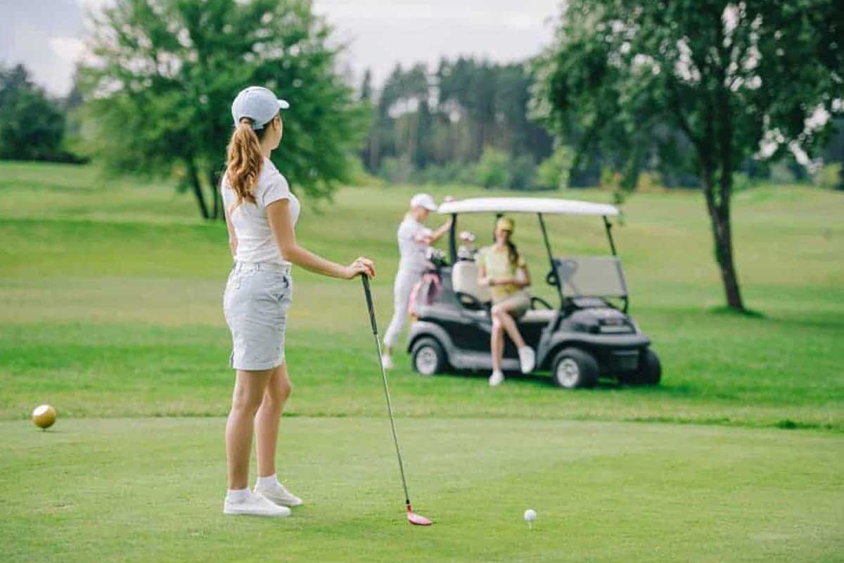 Golf Dress Code: What to Wear on the Golf Course 2 A woman is practicing golf drills to improve her game on the course while utilizing a golf cart.